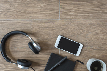 Top View of Notebook, Mobile Phone and Headphone on Wood Background.