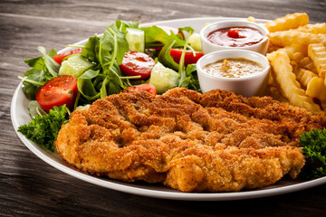 Fried pork chop, French fries and vegetable salad 