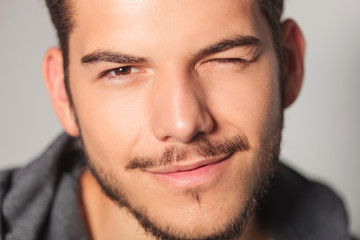 smilling young man is winking his eye