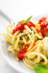 Homemade spaghetti pasta with avocado, tomato and basil sauce, closeup