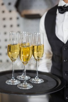 Bartender holding tray of champagne glasses in bar 