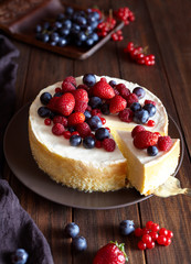 Homemade Creamy mascarpone cheesecake with berries forest fruits and strawberries on dark wooden table. Cream mousse cake.