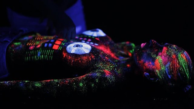 Topless girl painted in UV powder as a DJ panel.
