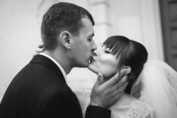 Bride and groom at wedding Day walking Outdoors near architecture. Bridal couple, Newlywed woman and man embracing with love