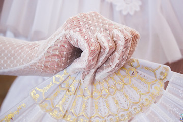 Girl in a lush white dress and in white gloves with beautiful hand fan