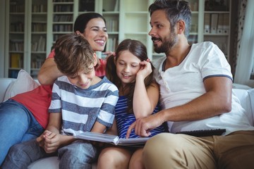 Smiling family sitting on sofa and looking at a photo album