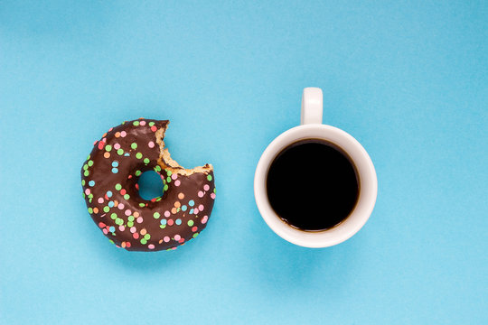 Chocolate donuts with cup of coffee on the blue background.