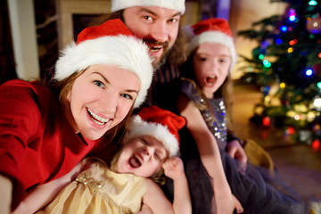 Fototapeta na wymiar Young happy family of four taking a photo of themselves on Christmas