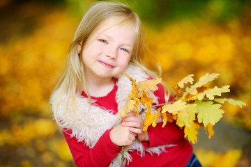 Naklejka premium Cute little girl having fun on beautiful autumn day
