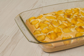 Sweet pie with peach in glass brazier on wood table.