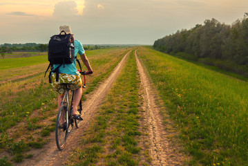 Obraz premium Young traveler riding bicycle on countryside on cloudy summer day