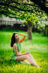 Naklejka na ściany i meble beautiful young woman sitting in a green garden