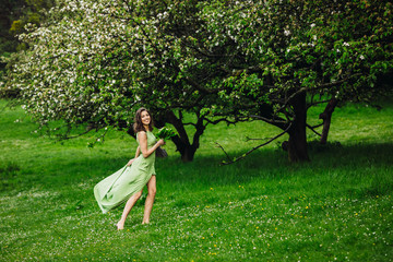 beautiful young woman walking in a green garden