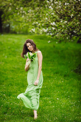 Naklejka na ściany i meble beautiful young woman walking in a green garden