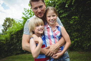 Father standing with their kids on grass in park
