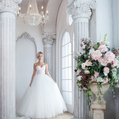 Obraz premium Charming young bride in luxurious wedding dress. Pretty girl, is near big window