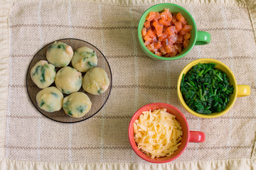 Muffins with salmon, spinach and cheese in black plate and ingredient for recipe in colorful cups. Aerial view.