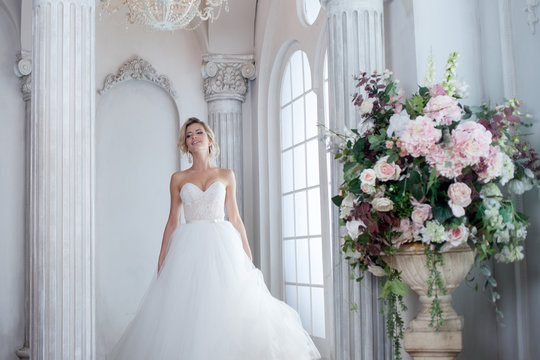 Charming young bride in luxurious wedding dress. Pretty girl, is near big window