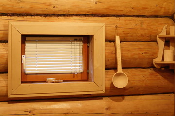 Окно, деревянный ковш и полка на бревенчатой стене в русской бане.
