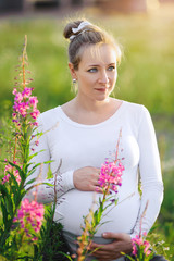 Young pregnant woman embracing her belly at sunset.