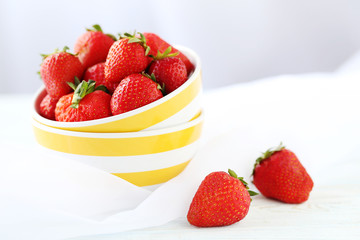Fresh and tasty strawberries in bowl on a white wooden table