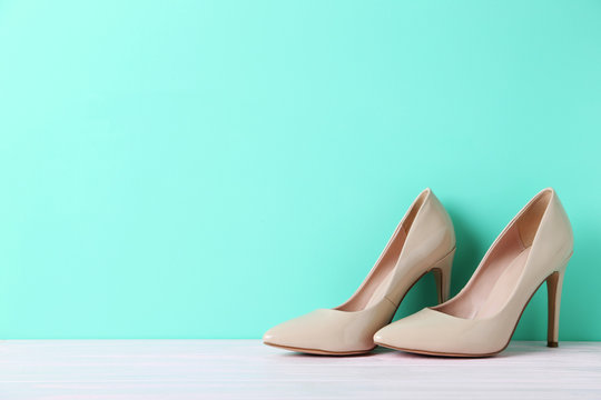 Pair of beige women's high-heeled shoes on wooden table
