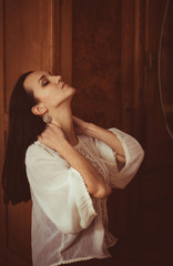 Fototapeta premium Daydreaming woman lies her hands over the neck while bending her