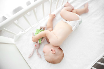 Little baby sleeping with toy rabbit on white bed