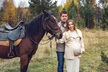 Obraz premium pregnant girl and her husband standing next to the horse