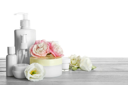 Different cosmetic bottles and eustoma flowers on white background