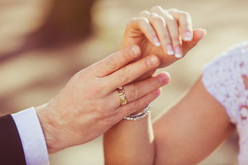 Broad groom's hand touches gently bride's wirst