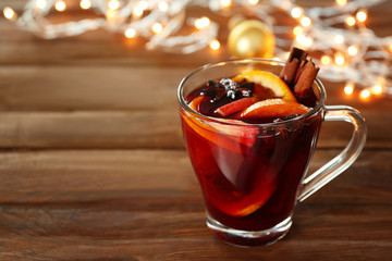 Glass cup of delicious Christmas mulled wine on wooden background, closeup
