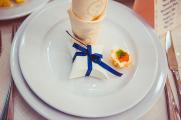 White box with blue ribbon stands on the white plate