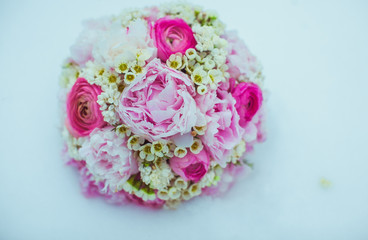 Gorgeous wedding bouquet made of pink peonies lies on the snow