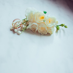 Obraz na płótnie Canvas Tiny white flowers lie behind golden wedding rings
