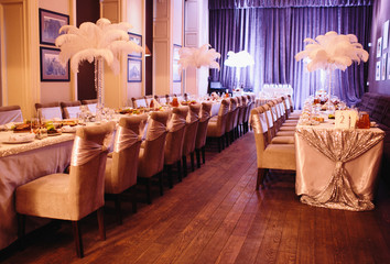 Vases full of white feathers stand on the dinner tables in the r