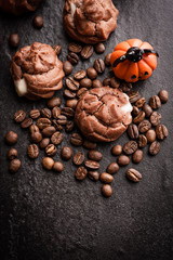 Eclairs and coffee beans with halloween decoration on black background