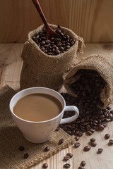 Coffee cup and coffee beans in bag on wooden