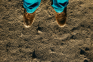 Male shoes on textured sand contrast blue trousers
