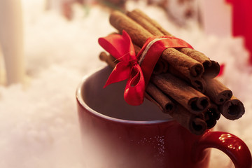 cinnamon sticks with ribbon on red cup. winter cozy moment. spac