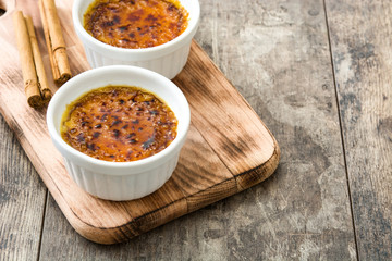 Traditional French creme brulee dessert with caramelized sugar on top, on wooden table

