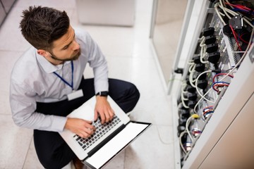 Technician using laptop while analyzing server