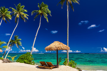 Two beach chair under umbrella with palm trees, Samoa