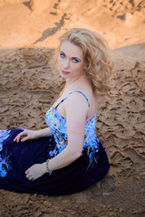 Portrait of a beautiful girl in a blue dress with handkerchief sand sky