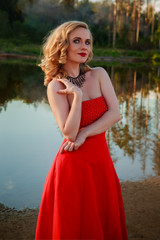 Fototapeta na wymiar Portrait of beautiful girl in red dress in nature