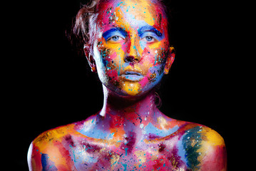 Portrait of a woman with colorful paint brushstroken on face. Bright blue eyes. Advertising Space
