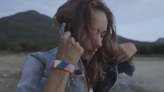 Sensual model with pink curly hair in denim jacket posing outdoors