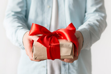 Man holding a present with craft paper box and red ribbon