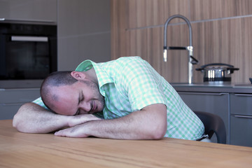 overweight man sleeping at kitchen table