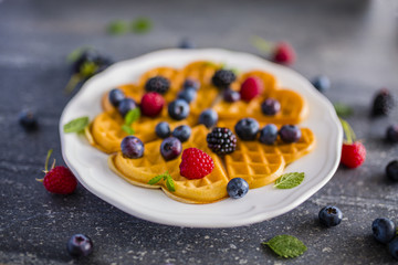 Homemade Belgian waffles with fresh ripe berries served on white plate. 